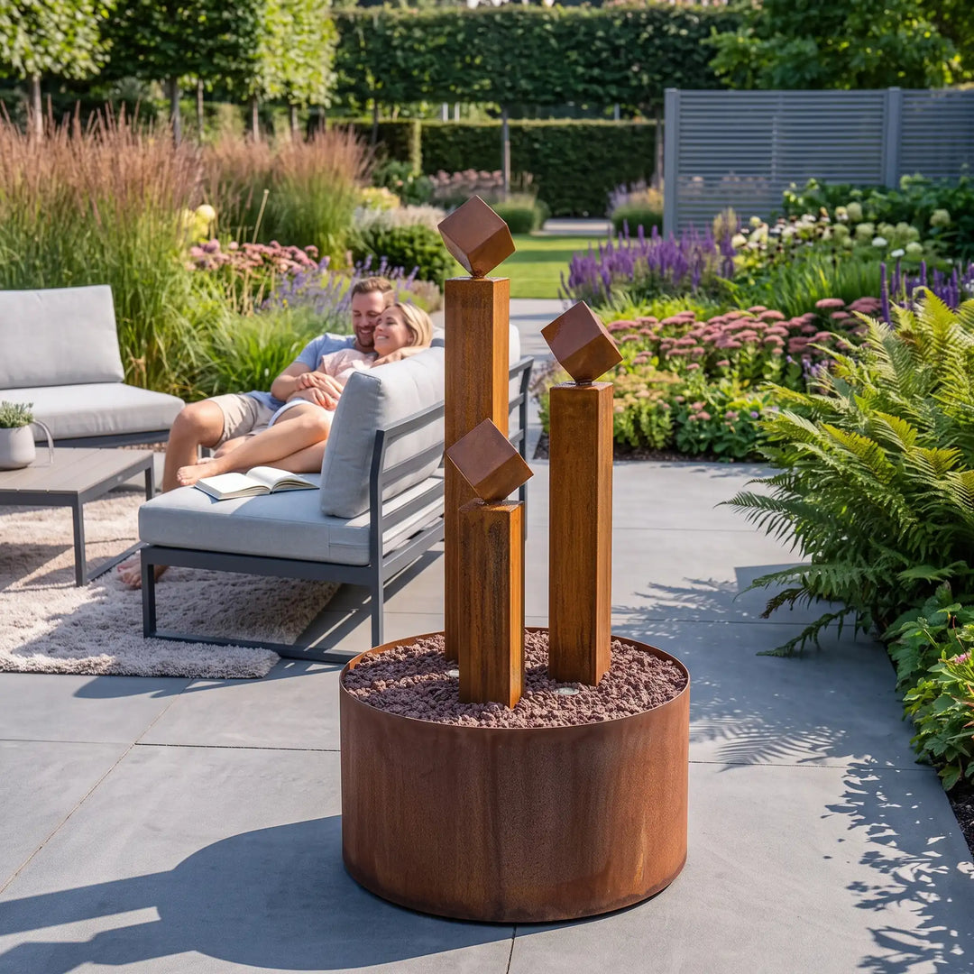Gartenbrunnen aus Cortenstahl mit drei Säulen und Würfeln auf Terrasse