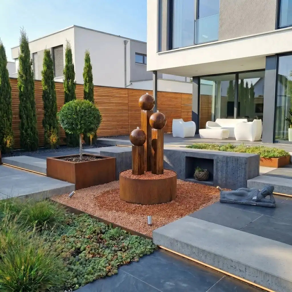 Cortenstahl-Gartenbrunnen Balance Sphera 125 cm im 3er-Set mit drei Kugeln auf einer Terrasse