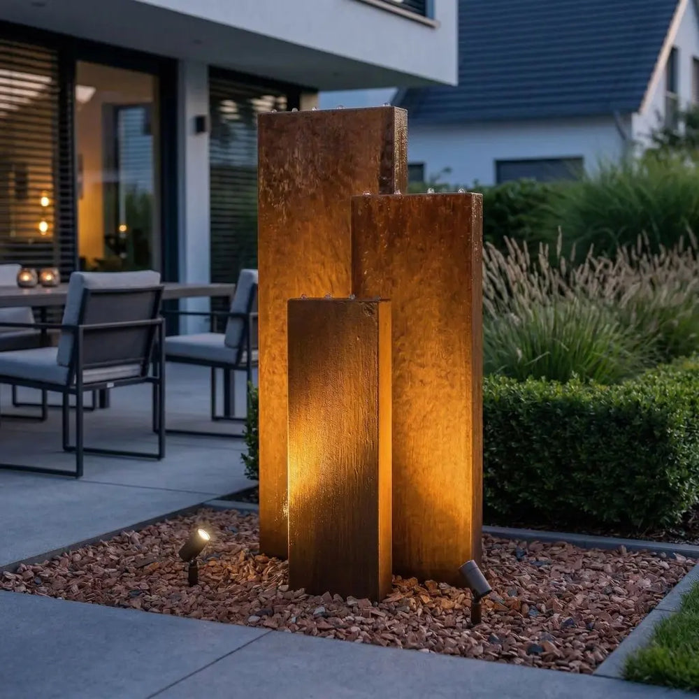 Cortenstahl-Gartenbrunnen Linea 150 cm bei Dämmerung mit externer Beleuchtung von unten
