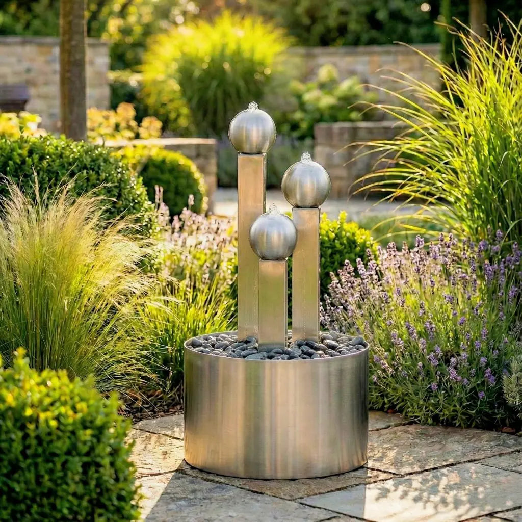 Drei abgestufte Edelstahlsäulen des Balance Sphera Gartenbrunnens in der Frontansicht