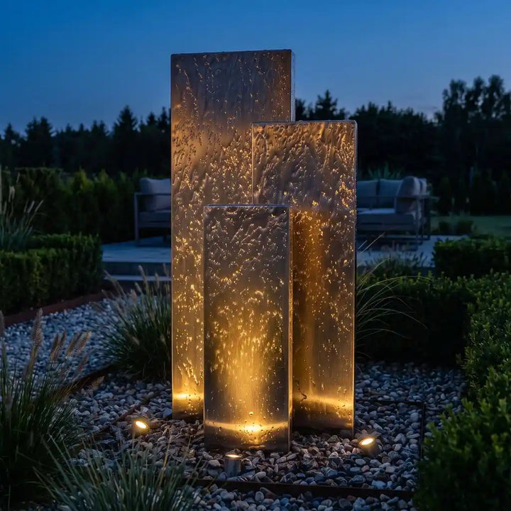 Edelstahl-Gartenbrunnen Linea 150 cm bei Dämmerung mit externer Beleuchtung von unten