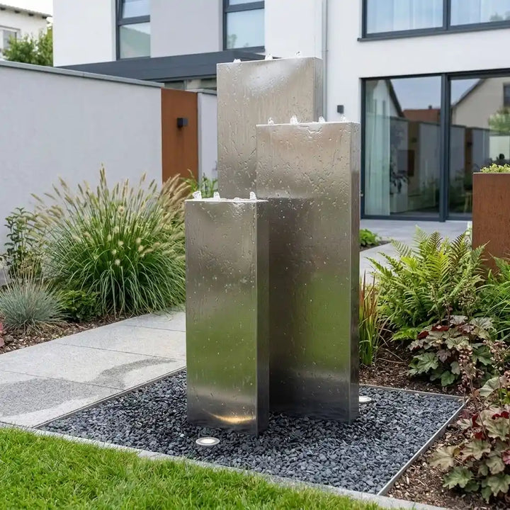 Edelstahl-Gartenbrunnen Linea 150 cm mit drei gestaffelten Säulen auf einer modernen Terrasse