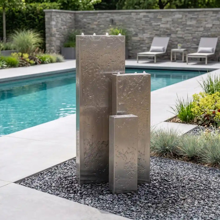 Edelstahl-Gartenbrunnen Linea 120 cm mit drei gestaffelten Säulen neben Pool