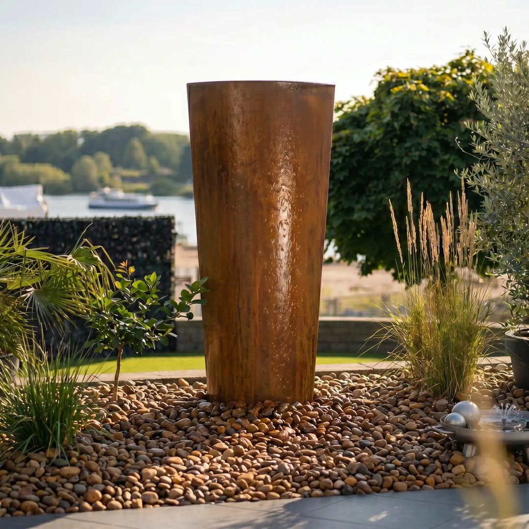 Gartenbrunnen Cortenstahl Komplettset: Das exklusive Modell Ellipse von Gaddia mit elliptischem Design und sanftem Wasserfluss auf der Terrasse.