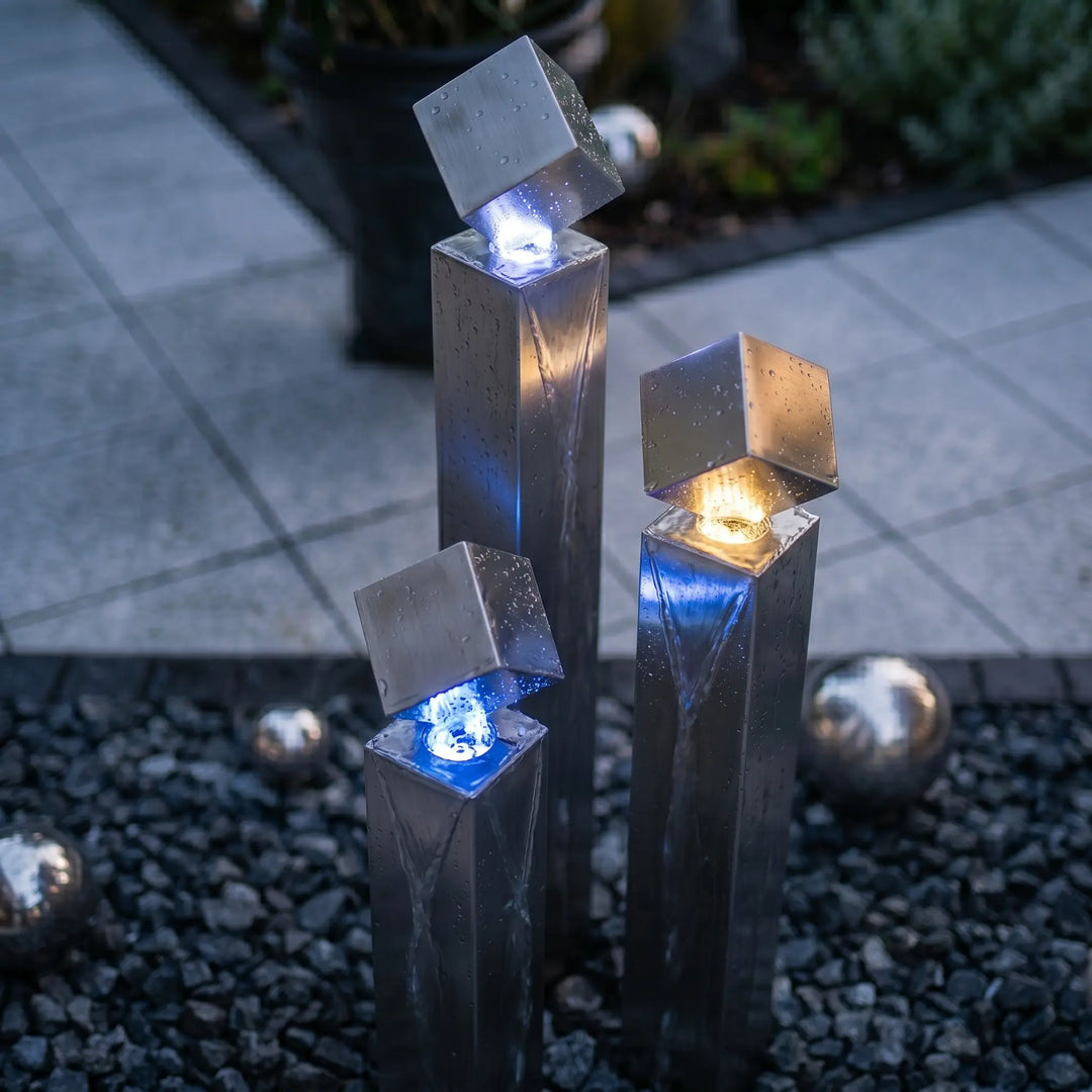 Edelstahlwürfel auf einer Säule des  Wasserspiels beleuchtet