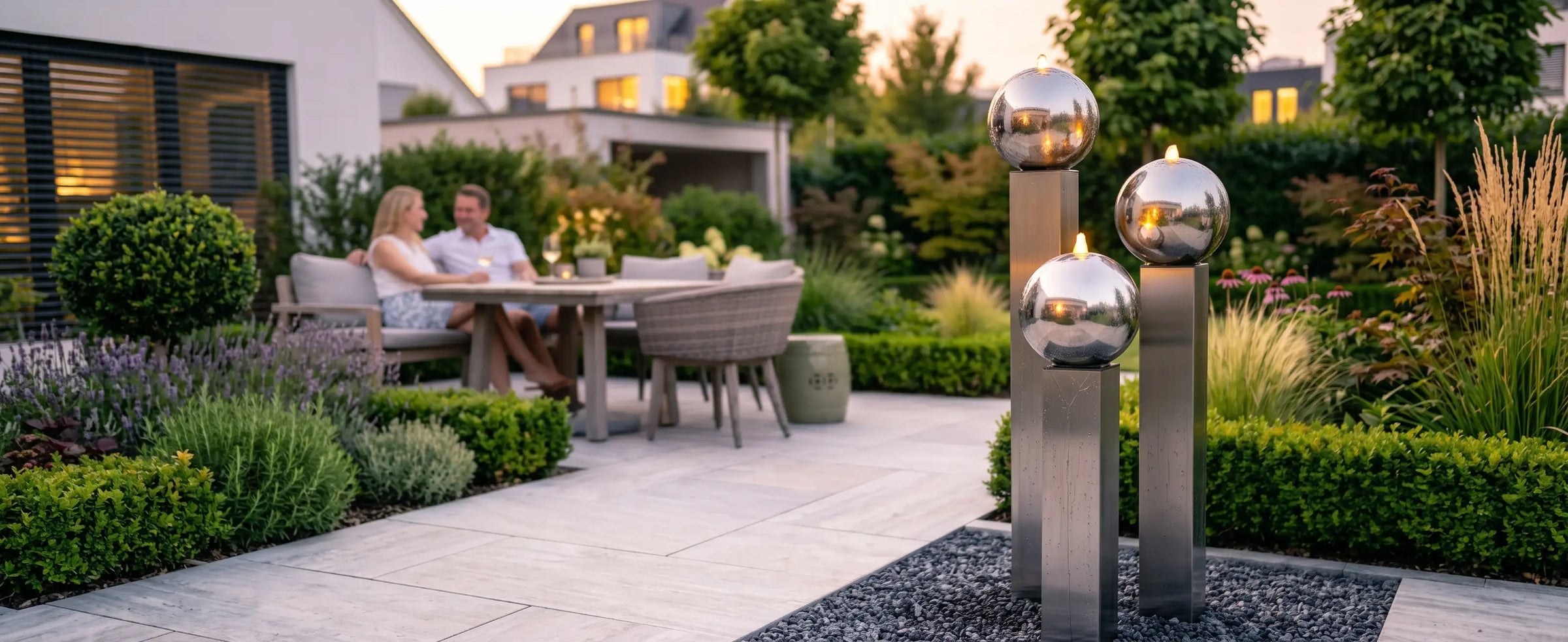 Balance Sphera Gartenbrunnen aus Edelstahl mit drei polierten kugeln beleuchtet in einem modernen Garten