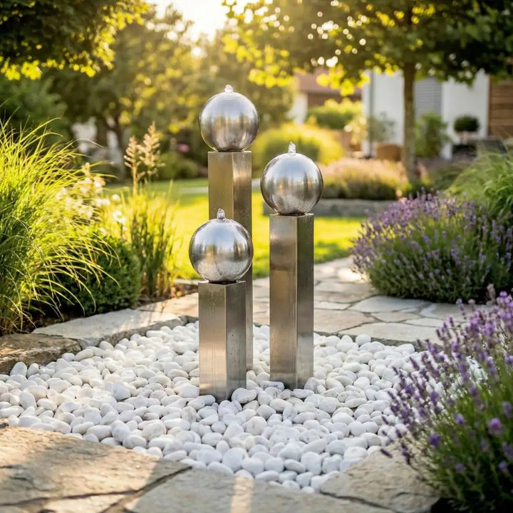Balance Sphera Edelstahl-Gartenbrunnen 75 cm mit drei Kugeln in einem bepflanzten Garten